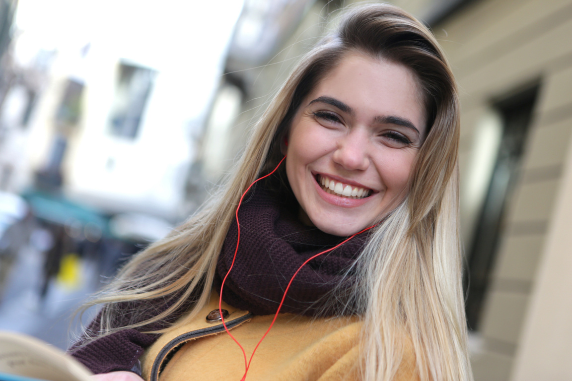 A Happy Woman in Purple Scarf Listening to Music